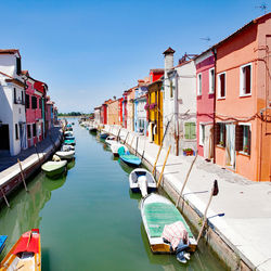 Boats moored in canal amidst buildings in city