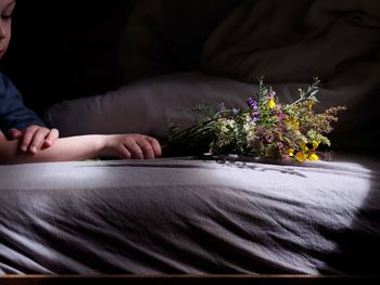 Cropped hand of child holding flowers on bed