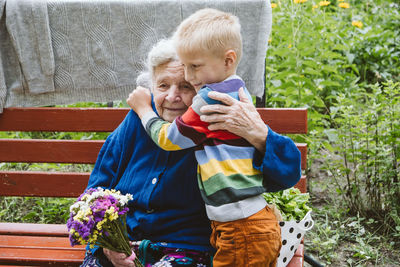 Grandmother and grandson embracing while sitting at park
