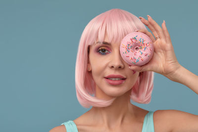 Portrait of young woman holding lollipop against blue background