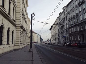 Road by buildings in city against sky