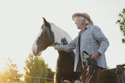 Senior man stroking horse at farm