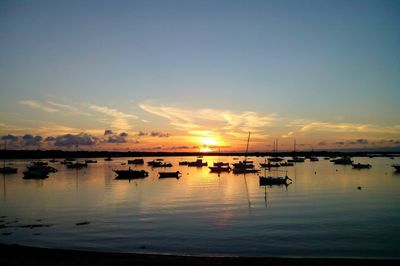 Silhouette boats in sea against orange sky