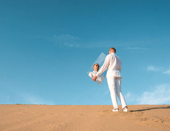 Rear view of man standing on field against clear sky