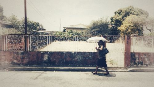 Side view of man holding umbrella against trees