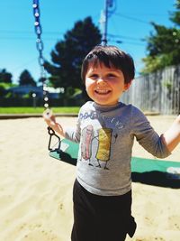 Portrait of happy boy holding swing at playground