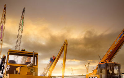 Yellow bulldozer, backhoe, and crawler crane parked at second-hand machinery auction yard.