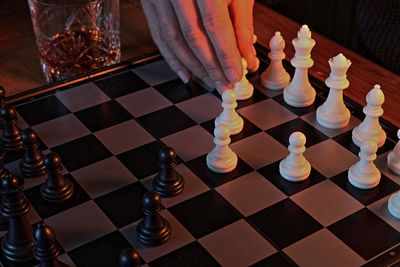 Cropped hand of person playing chess pieces on table