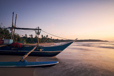 Fishing boat on sand beach at colorful dawn. coastline near tangalle in sri lanka