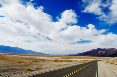 Empty road by landscape against sky