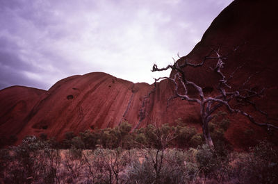 Low angle view of uluru against cloudy sky