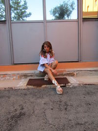 Full length of girl wearing sunglasses while standing against window