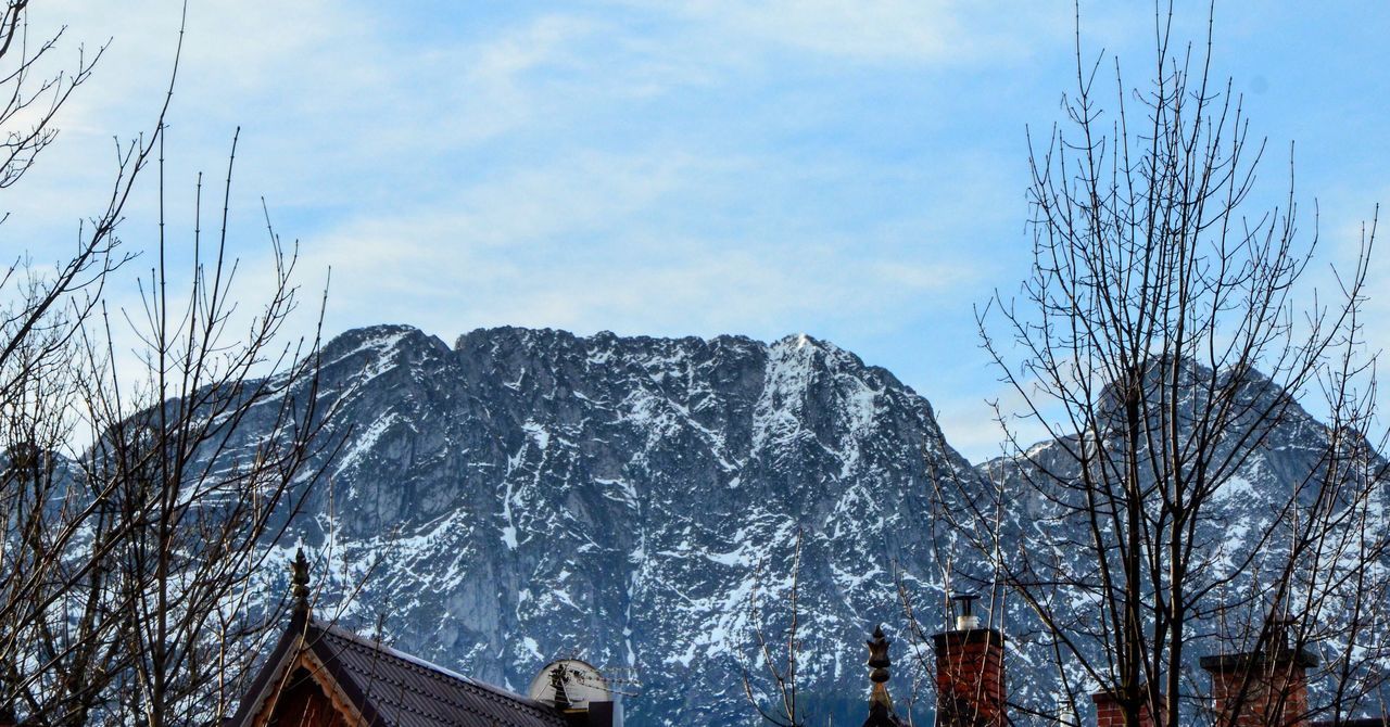 mountain, sky, snow, cold temperature, winter, nature, tree, cloud - sky, mountain range, tranquility, beauty in nature, scenics, low angle view, tranquil scene, building exterior, day, bare tree, outdoors, built structure, house