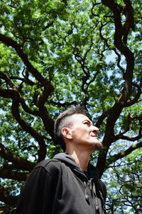 Low angle view of young woman against tree