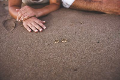 Cropped image of couple with rings on sand at beach