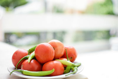 Close-up of tomatoes and chili peppers in plate on table