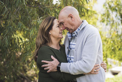 Portrait of grandfather and grandmother touching foreheads outside