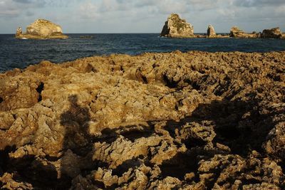 Shadow of person on rock formation by sea