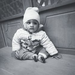 Portrait of cute baby girl sitting on sofa