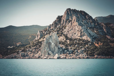 Scenic view of sea and mountains against clear sky