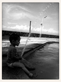 Side view of boy on shore against sky