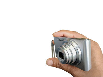 Close-up of hand holding camera against white background