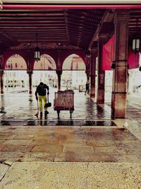 Rear view of people walking on wet road during rainy season