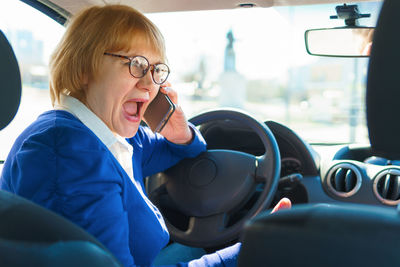 Woman using mobile phone while sitting in car