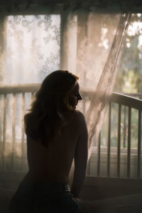 Rear view of woman looking through window