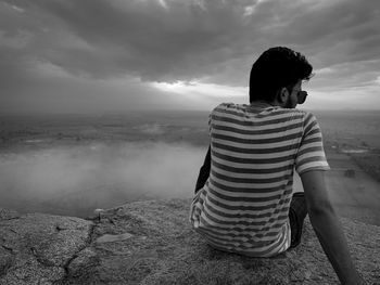 Rear view of man looking at camera against sky