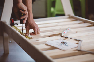 Cropped hands of man measuring wood at home