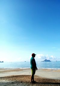 Rear view of man at beach against clear blue sky