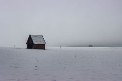 Building on snow covered land against sky