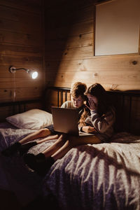 Woman using laptop on bed at home