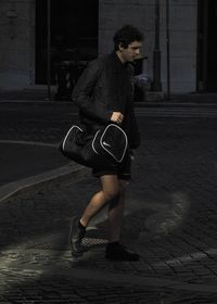 Young man looking away on footpath in city