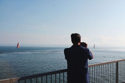 Rear view of man looking at sea against sky