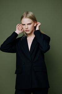 Portrait of young businesswoman standing against wall