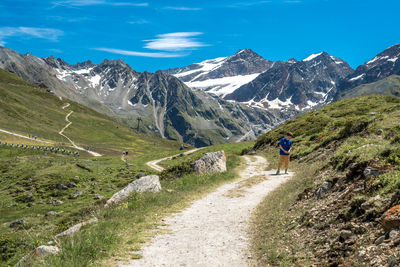Rear view of man walking on road against mountain range