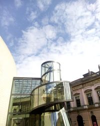 Low angle view of modern building against cloudy sky