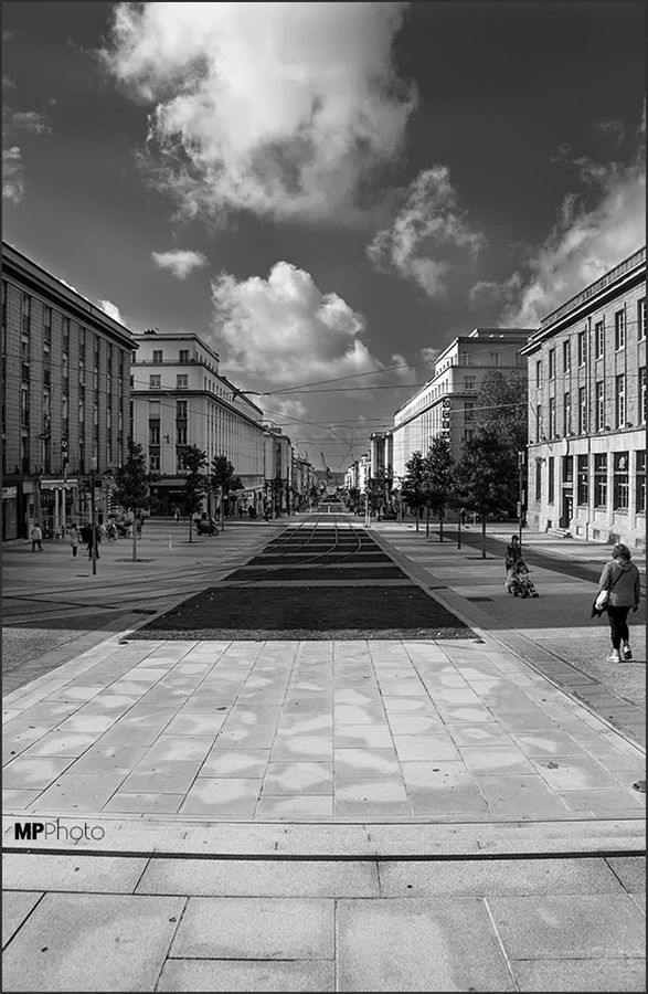 architecture, built structure, building exterior, sky, city, cloud - sky, the way forward, incidental people, cloud, diminishing perspective, street, city life, day, walking, cloudy, building, men, outdoors, transportation