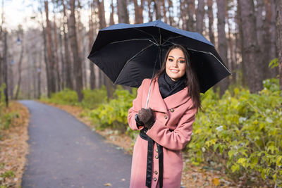 Young woman with umbrella on road during rainy season