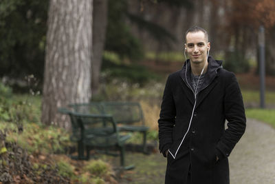 Portrait of young man standing against trees