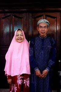 Portrait of senior couple standing against closed door