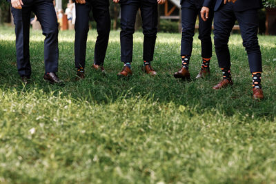 Low section of people walking on grassy field