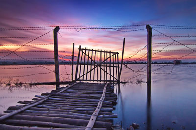 Bridge over sea against sky during sunset
