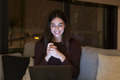 Young woman using mobile phone while sitting on sofa at home
