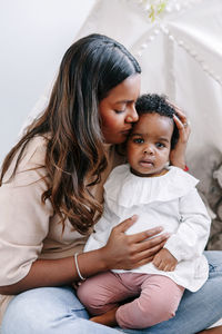 Happy indian mother playing kissing mixed race black baby girl daughter. ethnic diversity family