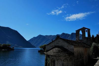 Built structure by mountains against blue sky