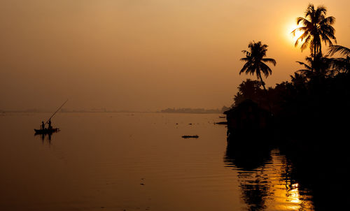 People sailing boat in sea against clear sky during sunset