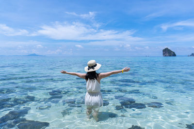 Rear view of woman standing in sea against sky